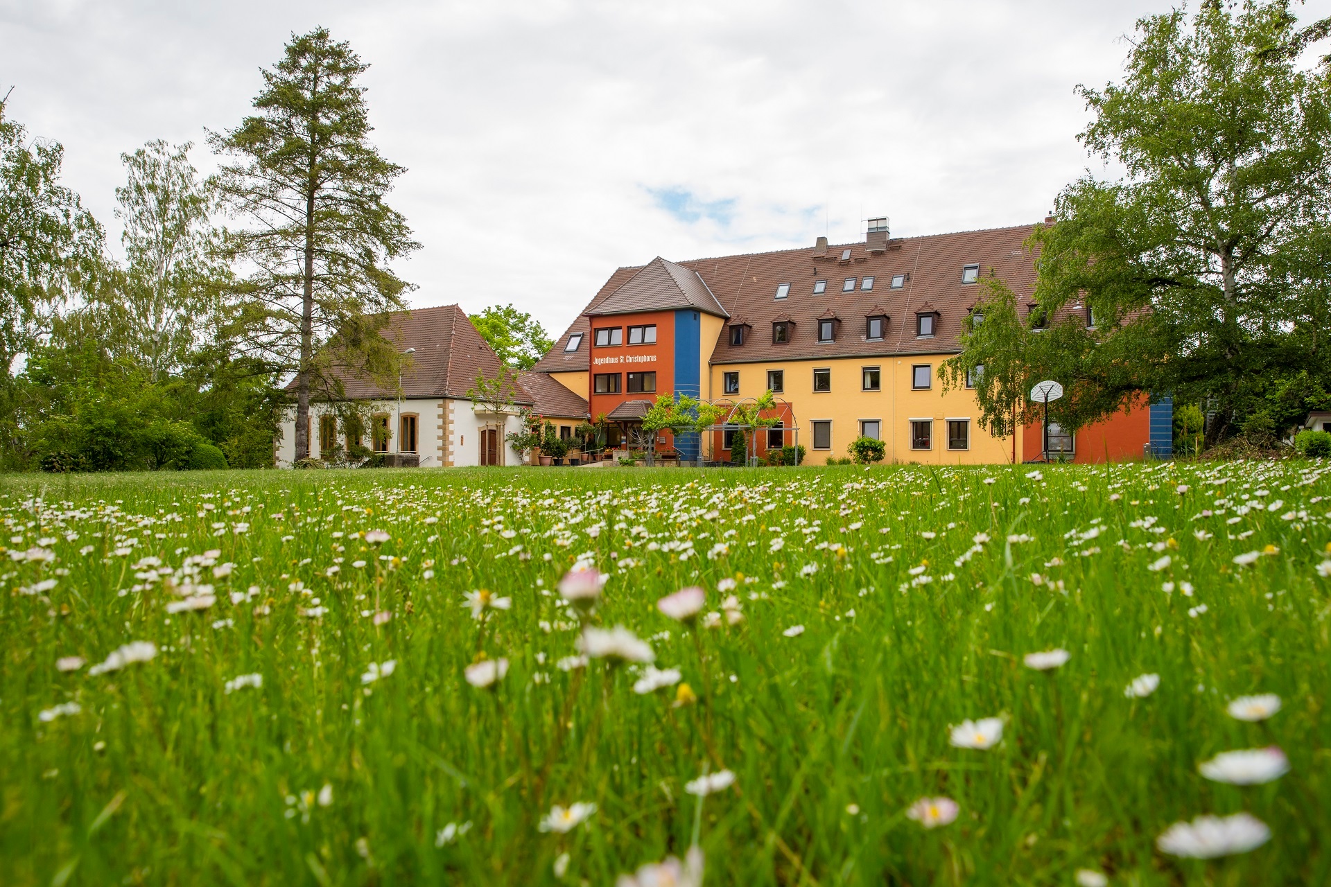 Außenansicht des St. Christophorus Jugendhauses, im Vordergrund ist eine Wiese zu erkennen.