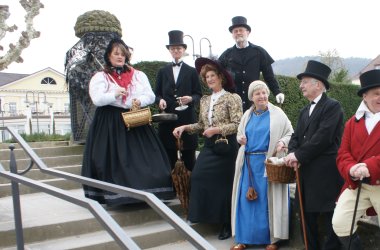 Kostümierte Gästeführer auf einer Sandsteintreppe am Valentin-Ostertag Brunnen.