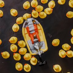 Ein kleines Plastikboot schwimmt auf der Isenach. Es ist umgeben von gelben Gummienten.