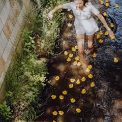 Weinprinzessin Lea Baßler läuft barfuß durch die Isenach. Um sie herum schwimmen gelbe Gummienten.