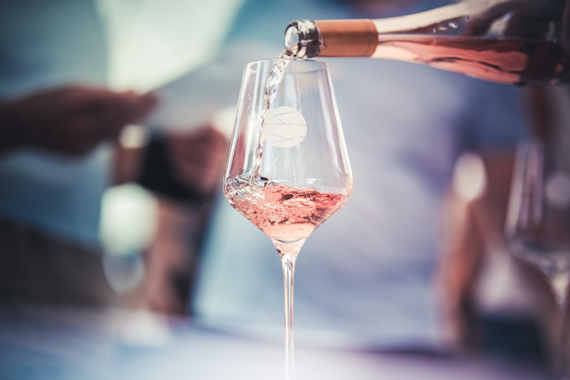 In ein Stielglas mit dem Logo des Forum Pfalz wird ein rosa farbener Rosé Wein eingeschenkt. 