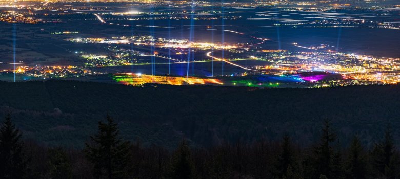 Das gesamte bunt beleuchtete Weinbergnachtgelände bei Nacht mit Laserstrahlern und Blick bis in die Rhein-Ebene und auf die basf