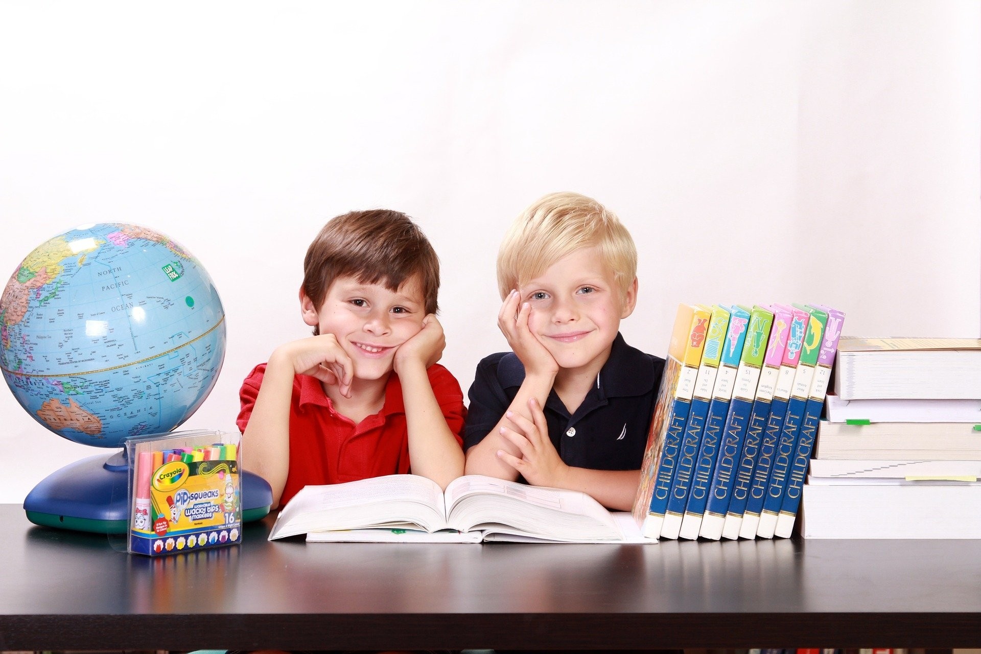 zwei Kinder am Schreibtisch mit Bücher und Globus