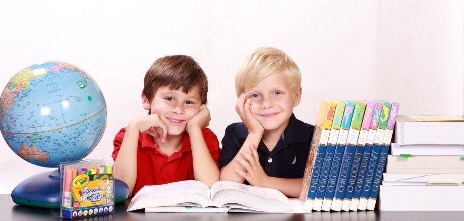 zwei Kinder am Schreibtisch mit Bücher und Globus