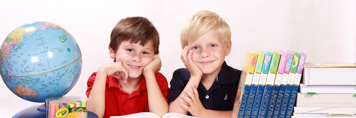 zwei Kinder am Schreibtisch mit Bücher und Globus