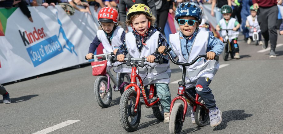 Die Kinder haben viel Spaß beim Laufradrennen der kinder Joy of Moving mini tour auf der Zielgeraden der Lidl Deutschland Tour 2025 in Kassel.