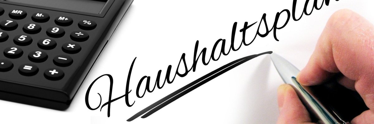 Schriftzug Haushaltsplan mit Taschenrechner und Geldmünzen