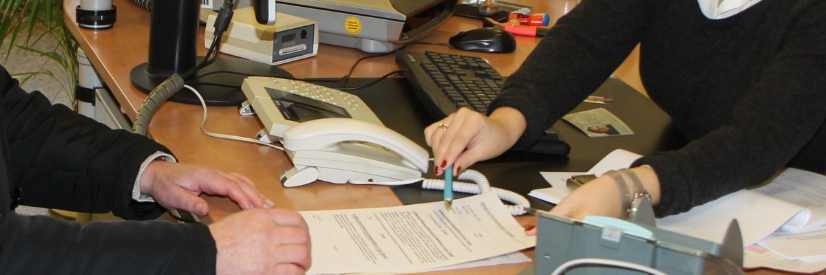 eine Mitarbeiterin des Bürgerbüros zeigt einem Bürger ein Formular