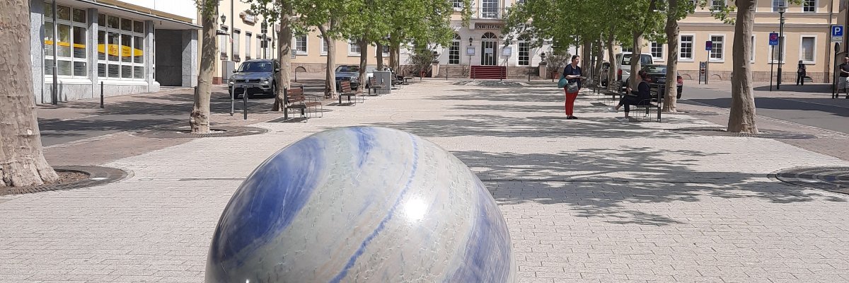 großer Parkplatz mit Baumallee und Kugelbrunnen